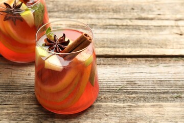 Tasty punch drink and spices in glasses on wooden table, closeup. Space for text