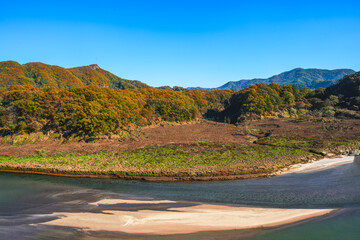 푸른 하늘과 강이 있는 갈색 단풍의 가을 들판