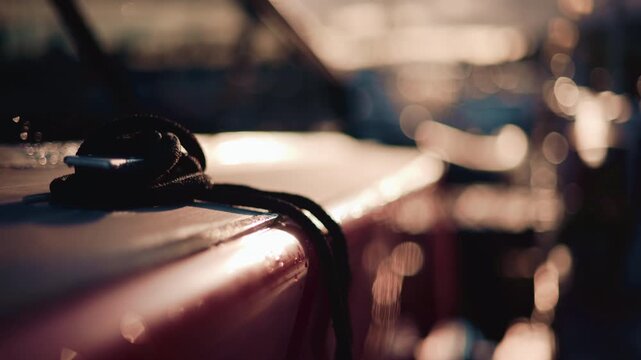 Close up of a boat deck during sunset, with a focus on a black rope coiled on the surface