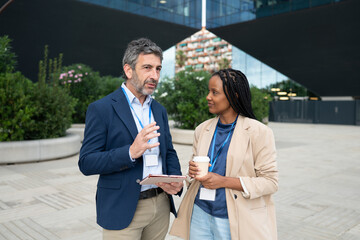 Male and female colleagues discussing work outdoors at a business event