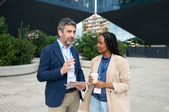 Male and female colleagues discussing work outdoors at a business event