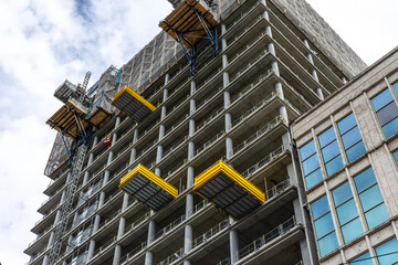 High rise under construction with cantilever decks and floor rhythm. Yellow platforms.