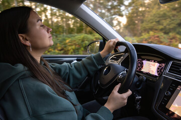 Young woman driving car in forest. Calm journey.