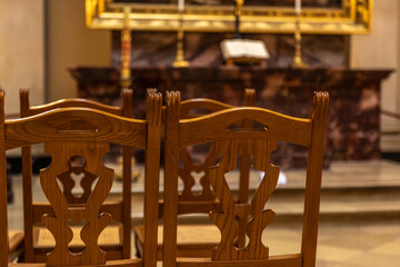 Silence of prayer in an old church. Wooden chairs before the altar.