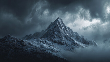 Obraz premium Majestic mountain peak shrouded in atmospheric clouds, evoking a sense of awe and wonder. The rugged terrain and dramatic weather create a striking landscape