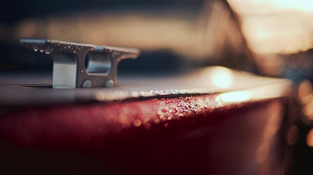 Close up of a boat cleat on a red hull, shining under warm evening sunlight