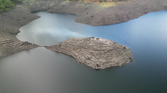 Aerial view of the ruins of Castro Candaz rise from the waters, stark against the surrounding landscape. Belesar, Spain - 02 November 2025