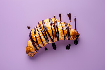 Croissant oblany czekoladą na fioletowym tle – apetyczne francuskie ciastko deserowe w nowoczesnej prezentacji.