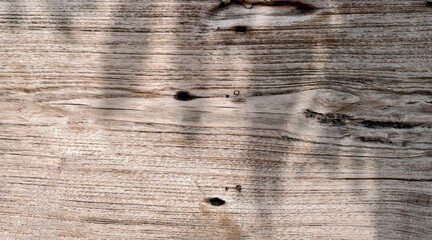 Close-up horizontal photograph of aged weathered wood grain. Surface features pale light brown...