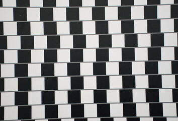 Classic black and white café wall optical illusion featuring a checkerboard pattern that makes parallel lines appear slanted. Striking visual illusion demonstrates how contrasting tones.
