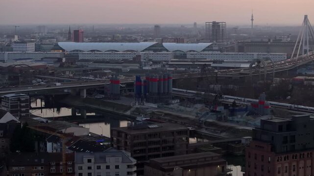 Urban panorama of Mannheim, Germany, with cars crossing Kurt Schumacher Bridge and trains leaving the central station at twilight