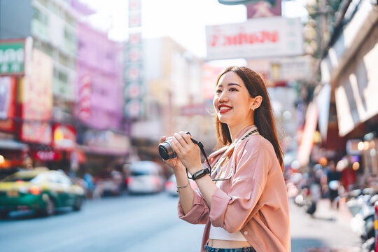 Asian woman traveller using digital camera travel at local city street market Yaowarat Bangkok, Thailand