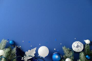 Winter holiday flat lay with frosted pine, silver leaves, blue and white ornaments, beads and stars...
