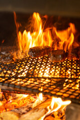 薪火で焼き上げる肉料理　炎が立ち上る炭火グリルの臨場感