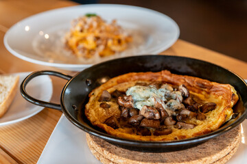 マッシュルームとチーズのオムレツがスキレットで提供される店内のテーブルシーン