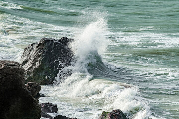 waves in stormy sea break with splashes on rocks
