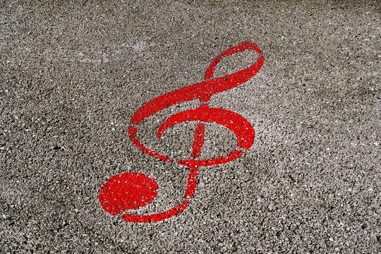 Clef de sol rouge dessin&eacute;e sur le sol. Symbole musical peint sur le goudron de la rue.
