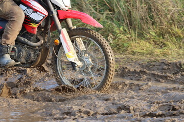 A motorcycle wheel in the mud on a country road