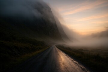 a straight road beside the green mountain coverd with fog and mist in early morning