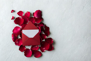 Red envelope surrounded by romantic rose petals on a white background