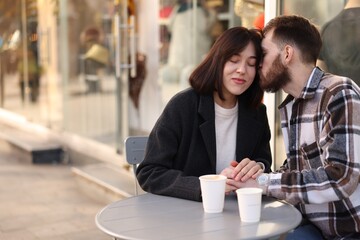 Affectionate couple holding hands in outdoor cafe. Space for text