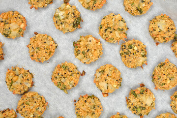 Golden-brown vegan patties, made from soy, onions, and seeds, are arranged on a parchment-lined baking sheet after being baked