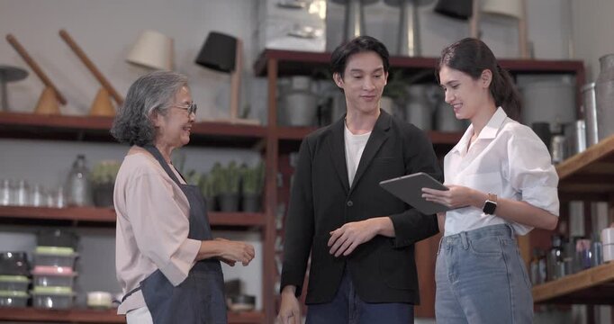 An Asian male investor and team meet with senior female owner at family business ceramic retail shop, negotiating and signing a partnership contract to expand retail and wholesale opportunities.
