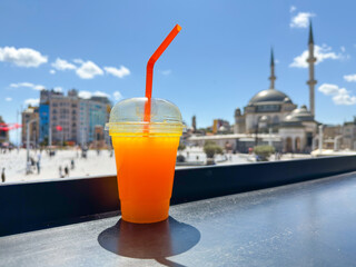 Fresh orange juice on street cafe table with view of Taksim Square and mosque on sunny summer day