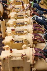 Row of yellow painted hydraulic or fuel injector pump modules on heavy machinery, showing serial numbers, bolts, and minor rust from storage or neglect.