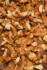A full frame close-up shot of a densely packed, unorganized pile of shelled walnut halves and pieces, showcasing their texture and color variation