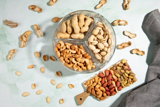 Top view of dried fruits cashews, peanuts and pistachios on kitchen countertop.