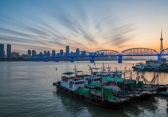 Naklejka premium Evening Scenery View with River, Modern Architecture, Bridge, and Anchored Boat