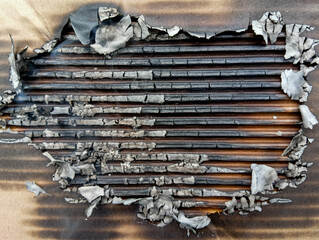 Close-up of burnt cardboard texture with ashes and charred layers, showing natural fire damage, smoke marks, and detailed surface for abstract design use.