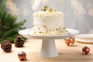 Delicious cake with Christmas decor on light wooden table against blurred lights