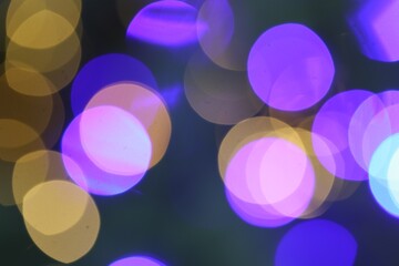 Beautiful blurred Christmas lights on color background, closeup. Bokeh effect