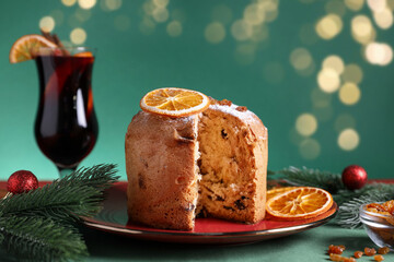 Christmas food. Delicious Panettone cake and festive decor on green background, closeup