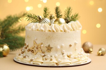 Delicious cake with Christmas decor on beige background against blurred lights, closeup. Bokeh effect