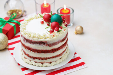 Delicious sponge cake with Christmas decor, gift box and burning candles on light table, closeup. Space for text
