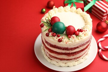 Delicious sponge cake with Christmas decor and berries on red background, closeup. Space for text