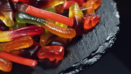 assorted jelly candies floating on black background.