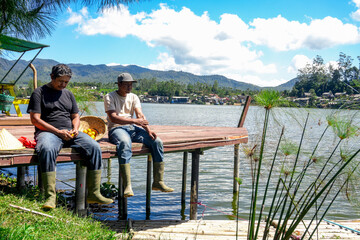 Tranquil Lakeside Scene Shows Two Men Enjoying Peaceful Moment Together While Fishing