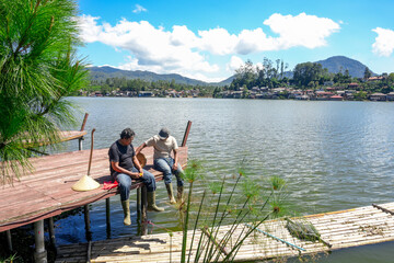 Two Friends Relax by Lake on Summer Day Enjoying Peaceful Scenery and Fresh Air