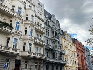 Low angle view of colorful old town buildings and autumn trees with bright leaves against a blue sky.
