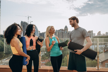 Multiracial group of friends gather to exercise on rooftop, outdoor yoga session
