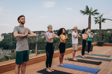 Quiet multicultural sportspeople practice mindfulness on hotel rooftop terrace