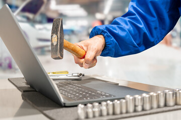 Furious manager at the auto repair shop  destroying his laptop with a hammer
