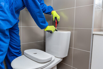 Repair man plumber fixing a toilet in the bathroom - home repair concepts