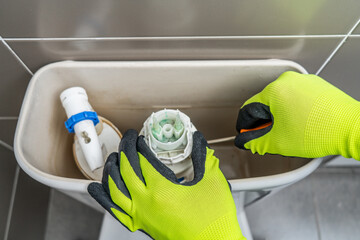 Close-up on a plumber fixing a toilet in the bathroom.Home repair concepts