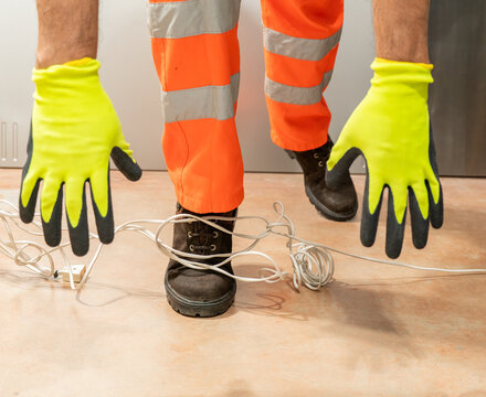 An industrial safety topic. A worker tripping over an electrical extension cord in an industrial environment at factory.