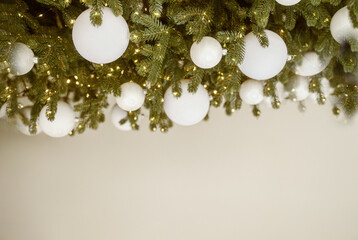 Christmas tree with white ornaments against a blurred background of lights
